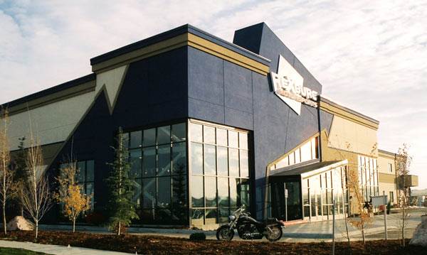 The dealership's storefront is blue and tan with a jagged shaped roofline and entrance.