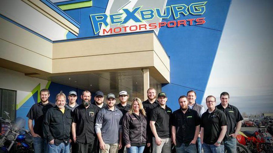Fourteen staff members line up before the Rexburg dealership's front entrance.